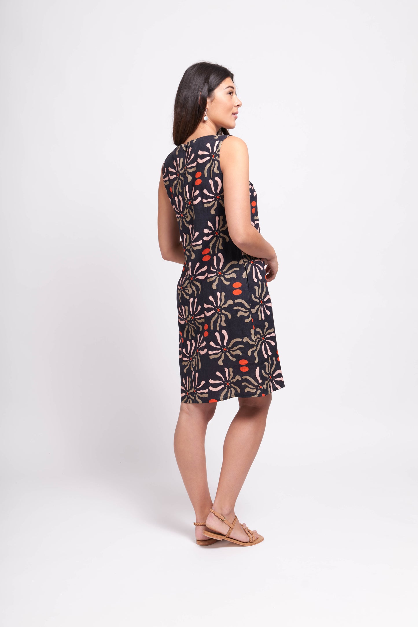 A woman in a Foil Floral Sun Keyhole Dress with Pockets and sandals standing against a white background.