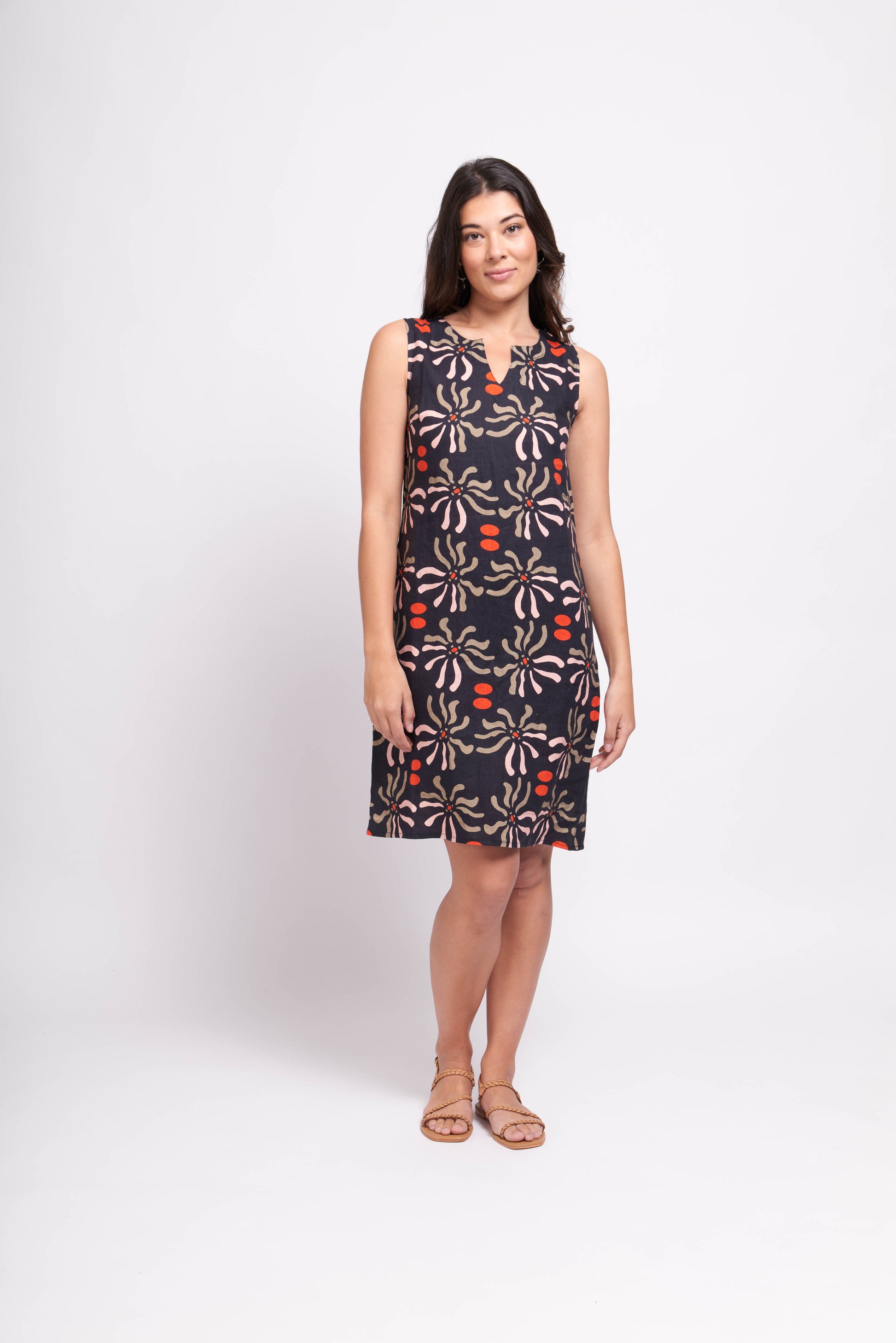 A woman in a Foil Floral Sun Keyhole Dress with Pockets and sandals standing against a white background.