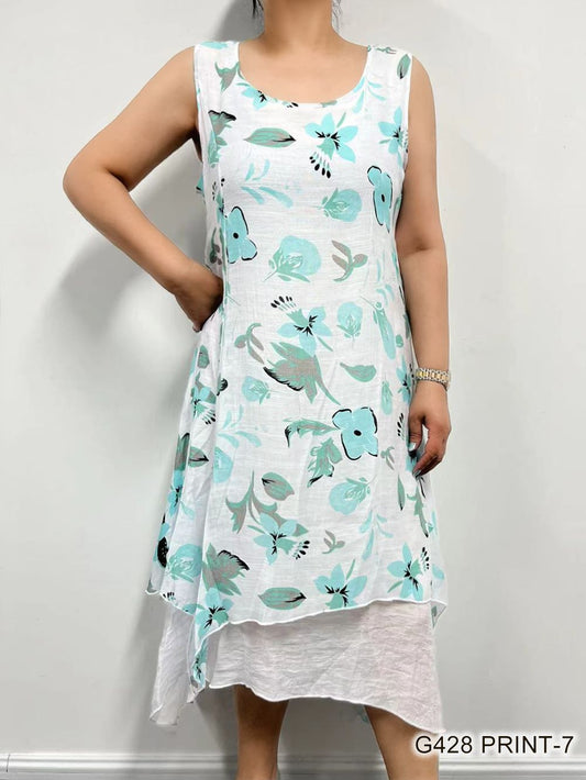 Woman modeling a sleeveless, asymmetrical Teal Floral Linen Dress by Fashion Cage with a floral and bird print pattern.