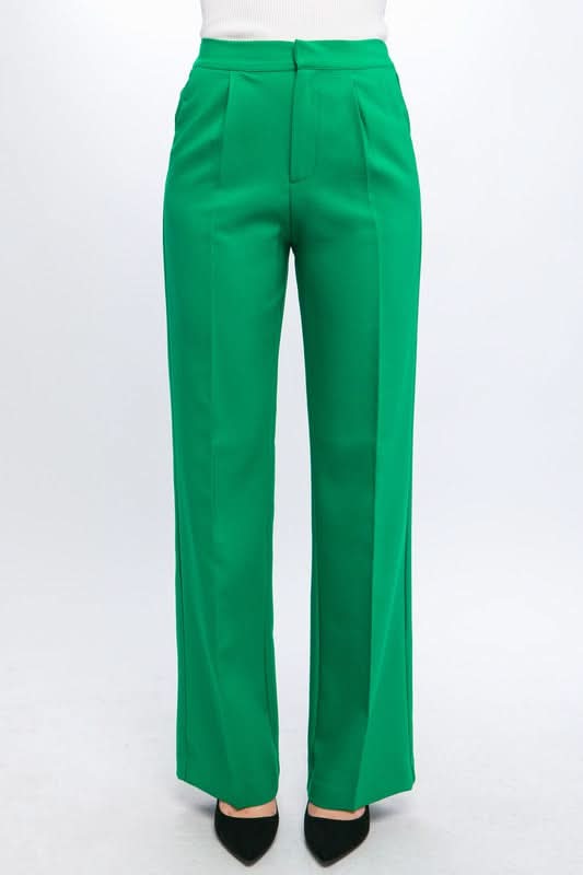 A person wearing Vanilla Monkey Dress Pant with Elastic Back in bright green and black pointed-toe shoes. The background is plain white.