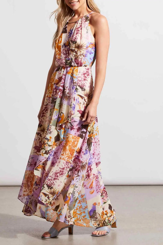 A woman wearing a flowing, floral Tribal maxi dress with halter neckline, posing in a studio setting.