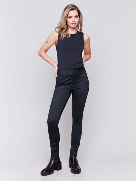 Person showcasing effortless style in a beige ribbed sweater and Charlie B's black and brown plaid Reversible Pull On Pants, paired with black ankle boots.