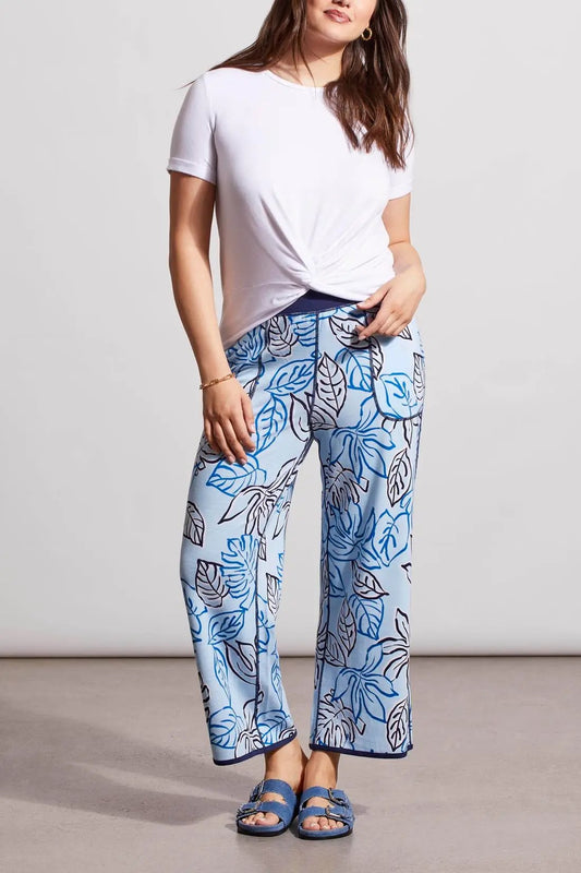 Woman wearing a white knot-front t-shirt and Tribal's blue patterned Reversible Crop Wide Leg Pants with matching slide sandals.