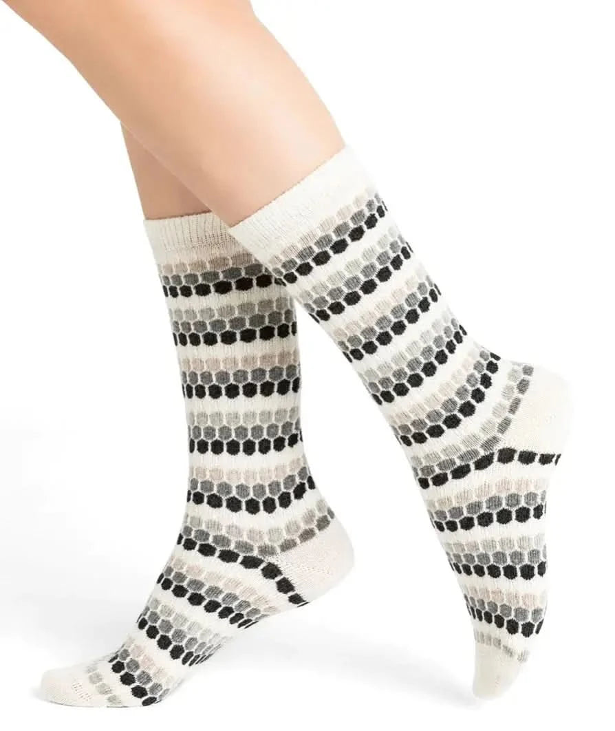 A woman sitting on a green couch wearing Bleuforet 6379 Laine & Cashmere Socks.