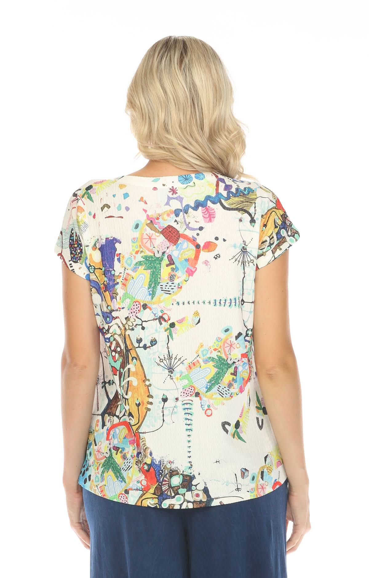 A woman with blonde hair, seen from the back, wears an Inoah Short Sleeve Crew Neck Top featuring a colorful abstract pattern and dark blue pants, standing against a white background.