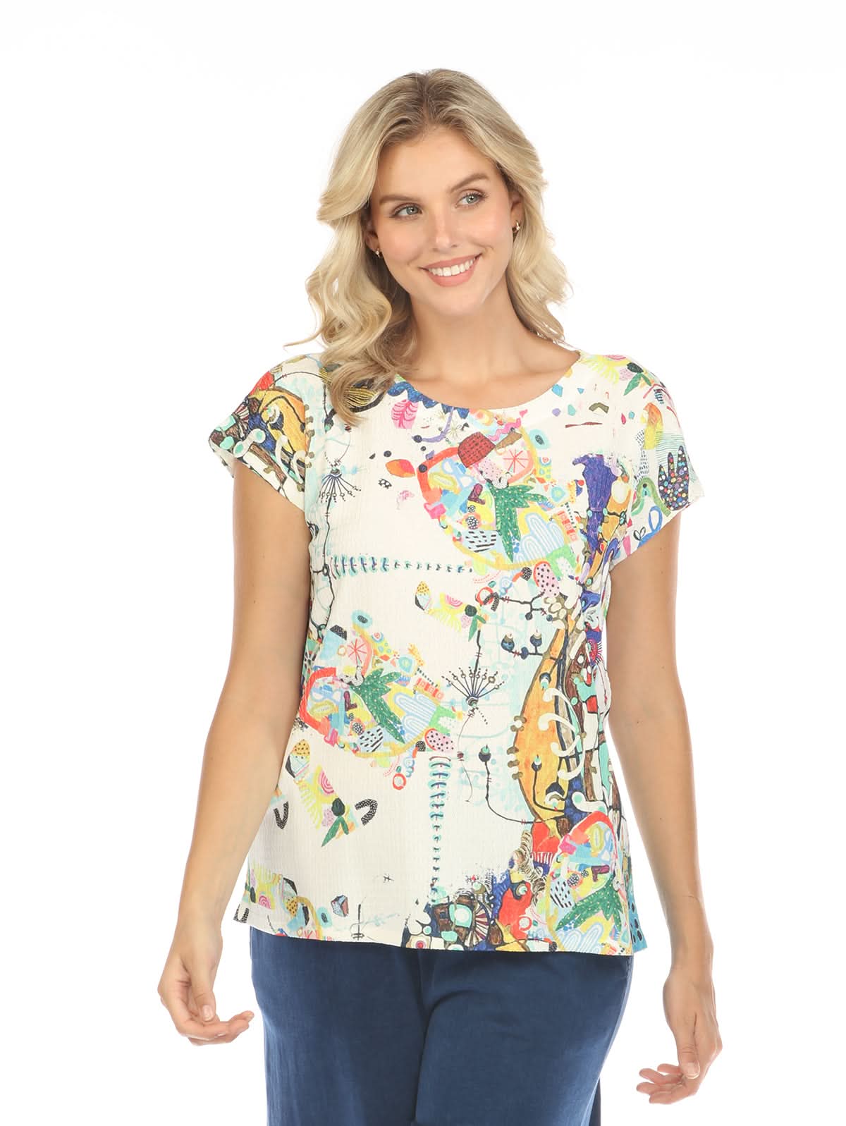 A woman with blonde hair, seen from the back, wears an Inoah Short Sleeve Crew Neck Top featuring a colorful abstract pattern and dark blue pants, standing against a white background.