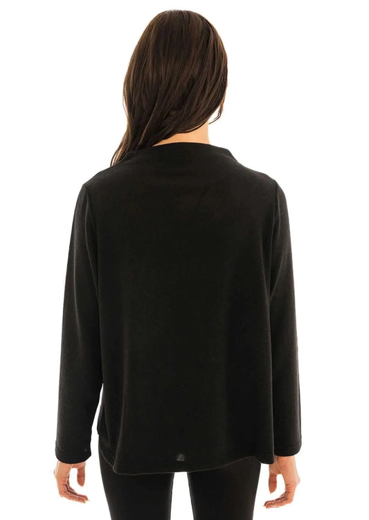 A person exudes fashion-forward elegance with one hand on their hip, wearing the sleek, long-sleeved Trisha Tyler Contrast Stitch Detail Sweater paired with matching black pants.
