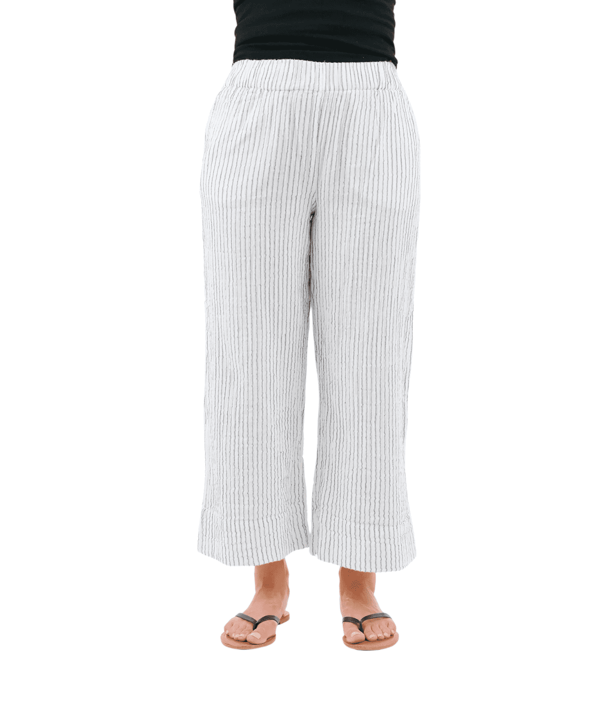 A person wears the Shannon Passero Yucca Crop Pant in white with subtle vertical stripes, paired with a black top and black sandals, standing against a plain white background.
