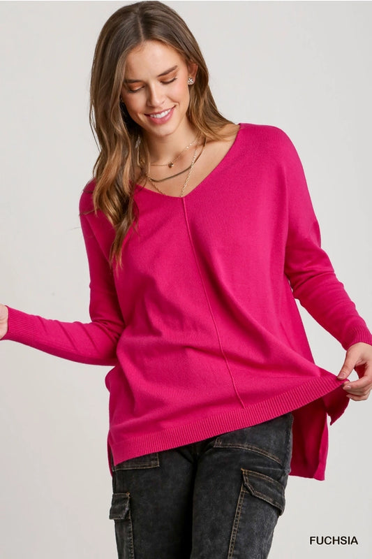 A woman wearing a pink Vanilla Monkey V-Neck Knit High Low Hem Sweater Top with Side Slit.