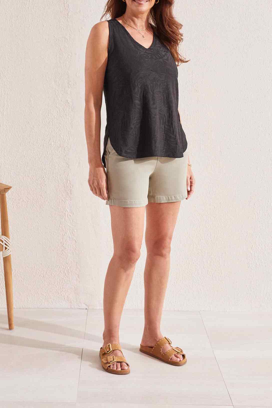 Woman smiling while wearing a stylish sleeveless Tribal V-Neck Tank Top with Curved Hem and beige pants.