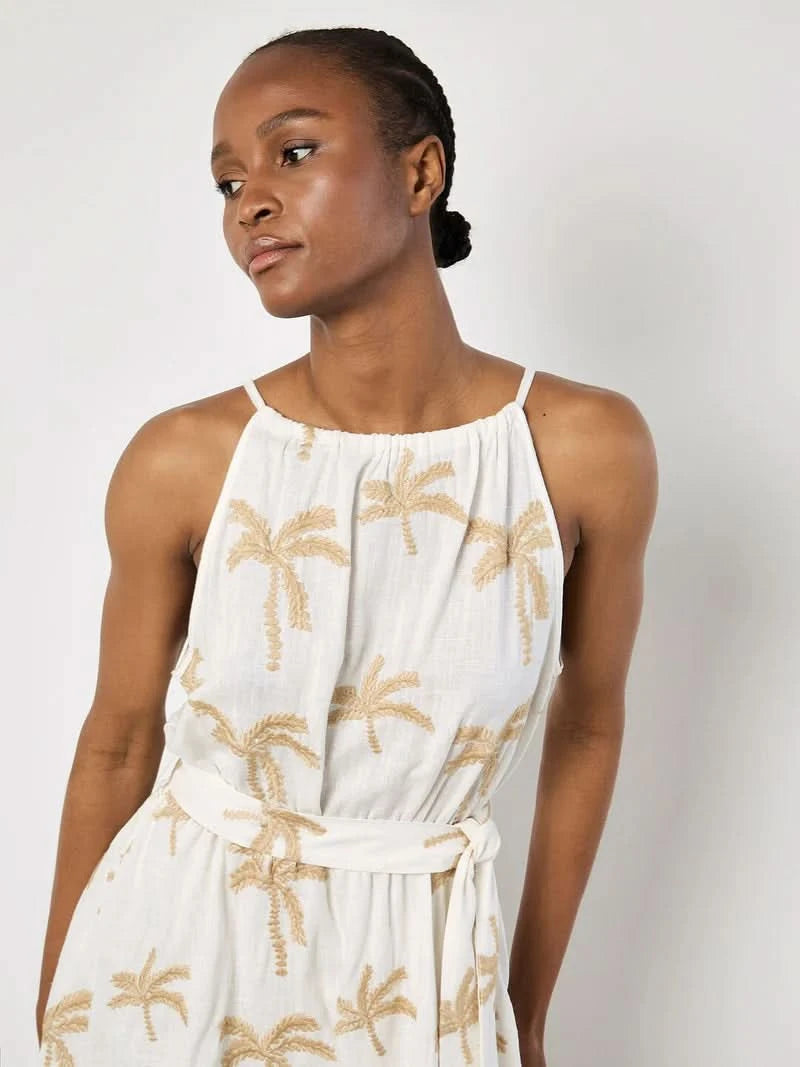 A woman in the Apricot Embroidered Palm Dress, featuring a breezy silhouette and beige palm embroidery, stands against a plain light background.