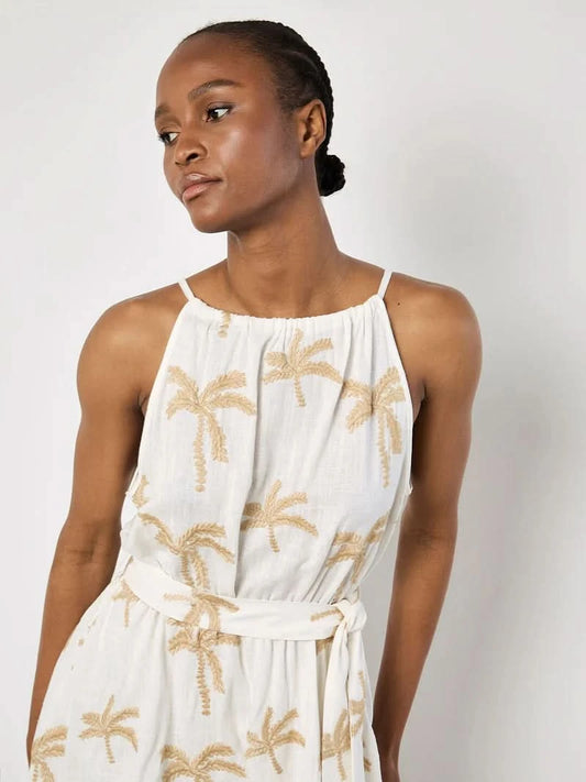 A woman in the Apricot Embroidered Palm Dress, featuring a breezy silhouette and beige palm embroidery, stands against a plain light background.