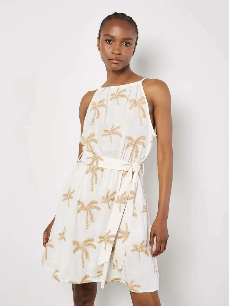 A woman in the Apricot Embroidered Palm Dress, featuring a breezy silhouette and beige palm embroidery, stands against a plain light background.