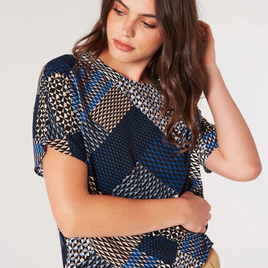 Woman posing in an Apricot Mino Geo Patchwork Top with her hand in her hair.
