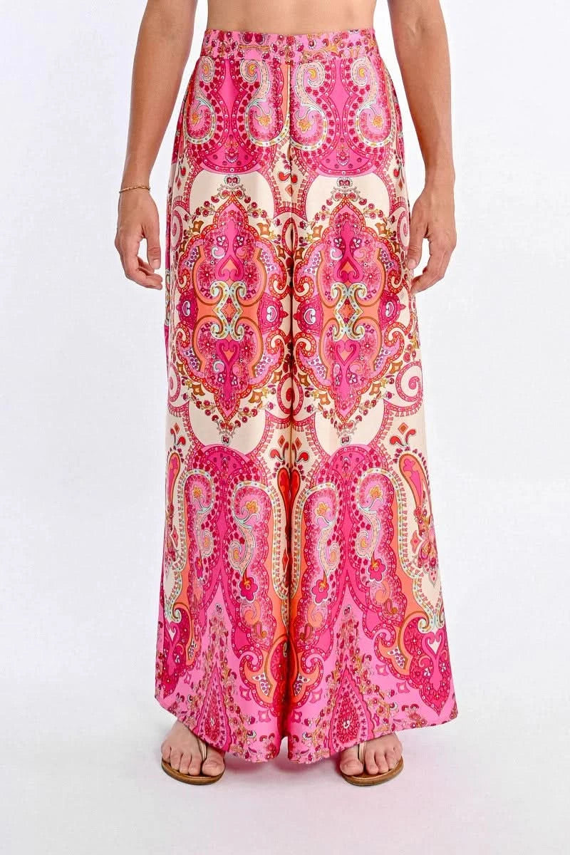 A person models Molly Bracken's vibrant Printed High Waist Pant, featuring a bohemian print with colorful pink, orange, and white paisley designs.