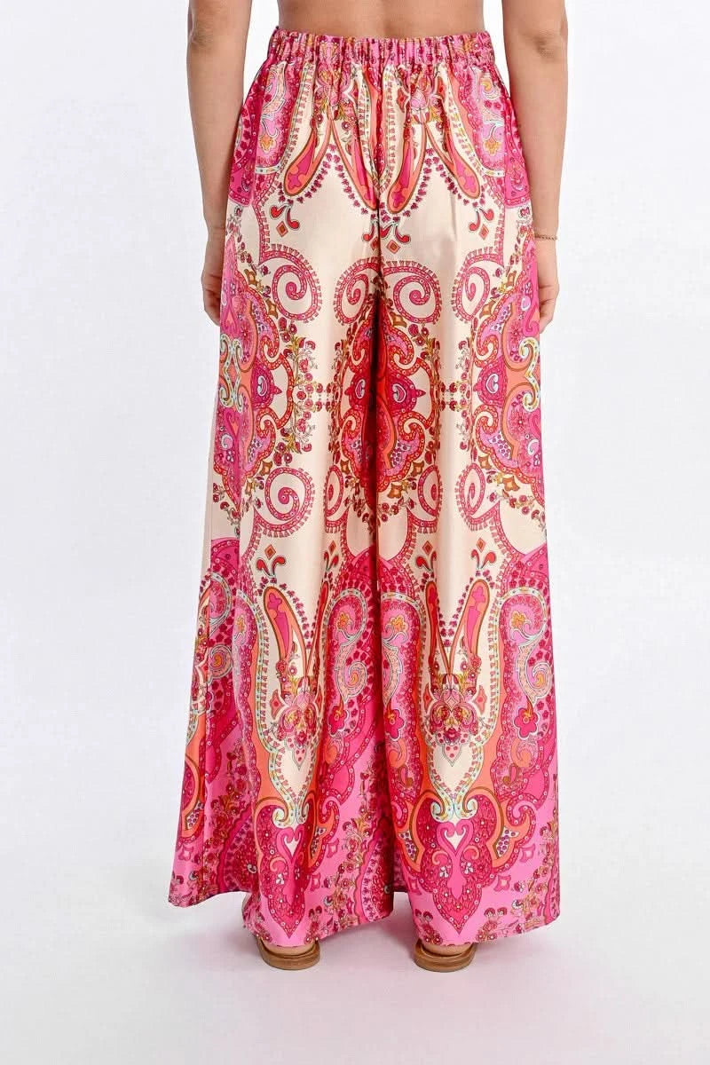 A person models Molly Bracken's vibrant Printed High Waist Pant, featuring a bohemian print with colorful pink, orange, and white paisley designs.