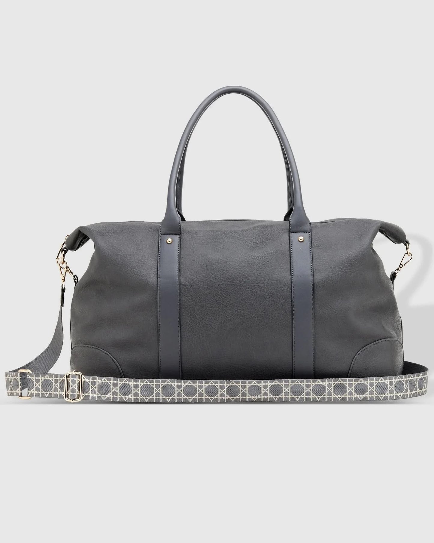 The Alexis Ezra Weekender Travel Bag by Louenhide is a large, dark gray bag made from vegan leather. It features two top handles and an adjustable, patterned shoulder strap.