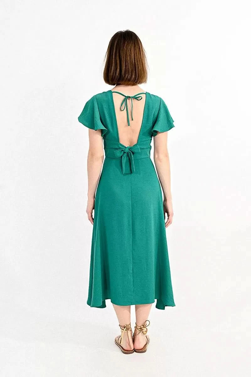 Woman posing in a stylish green Molly Bracken Long Cross-Bust Dress with capped sleeves and strappy sandals.