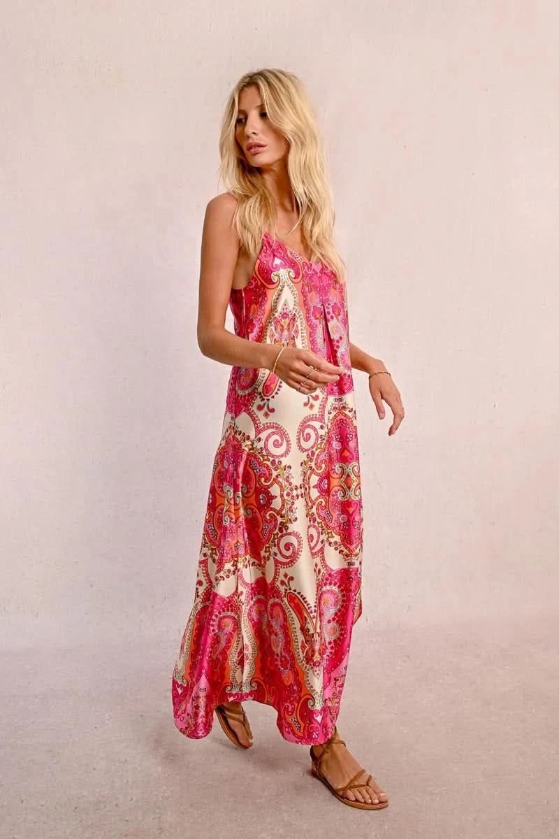 Against a plain light background, an elegant person with long hair is seen wearing a Satin Dress With Straps by Molly Bracken, along with brown sandals.