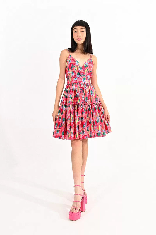 A woman in a Molly Bracken Printed Fit and Flare Dress with a back bow tie and pink heels stands against a white background.