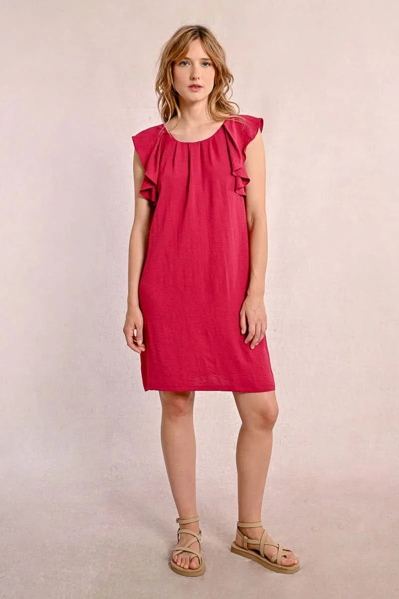 Against a neutral background, someone wears Molly Bracken's knee-length Round Neck Back Tie Short Dress with ruffled sleeves in red, paired with beige sandals.