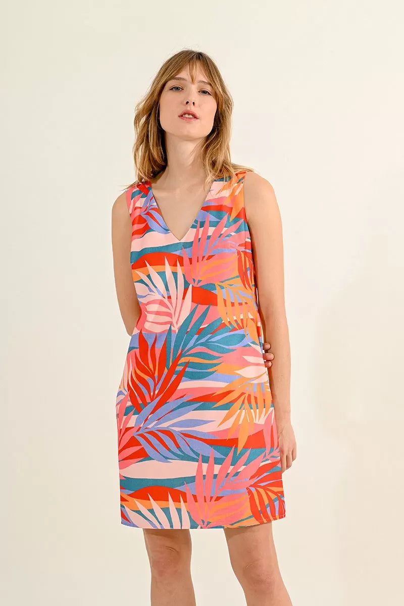 Woman posing in a Molly Bracken Tank V Neck dress with a vibrant tropical print and beige strapped shoes suitable for the summer season.