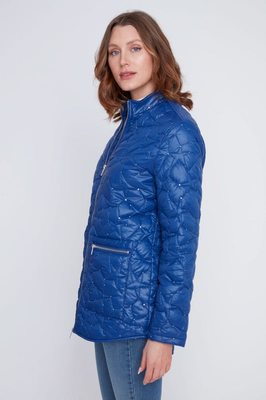 A woman stands with arms crossed, wearing the CoCo Y Club Woven Puff Jacket in blue, featuring zippered pockets, over a white top and blue jeans against a plain light background.