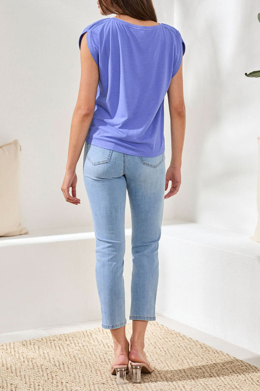 A woman wears the Tribal Boatneck cap sleeve top in purple, featuring pleated shoulders and a loose cotton blend fit, paired with light blue jeans against a neutral background.