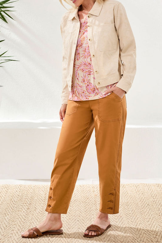 A woman wears the Tribal Floral Textured Jacket, a light beige, long-sleeve button-front piece with front pockets and floral embroidery, styled with high-waisted brown pants.