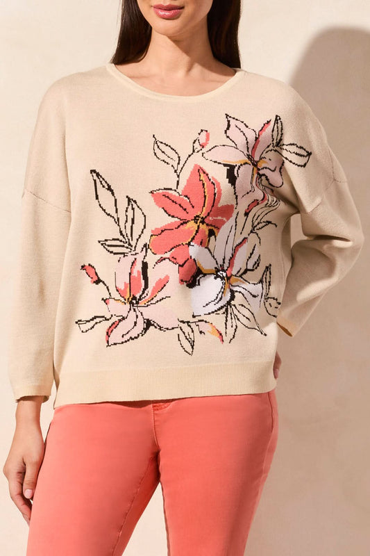 A woman wears the Tribal 3/4 SLEEVE CREW NECK SWEATER featuring a large pink floral design, paired with coral pants.