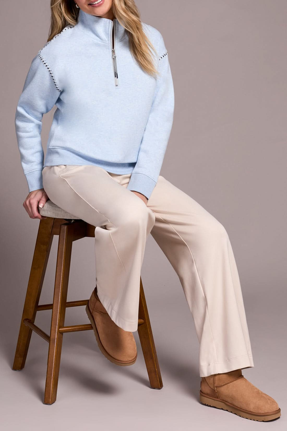 A person models the Tribal ZIP FUNNEL NECK TOP in light blue, paired with beige wide-leg pants and tan suede slippers, standing against a plain background.