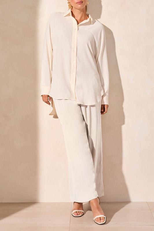 A person wearing the Tribal FLOWY RAGLAN SLEEVE SHIRT in brown, paired with loose-fitting pants, stands against a plain light-colored background.