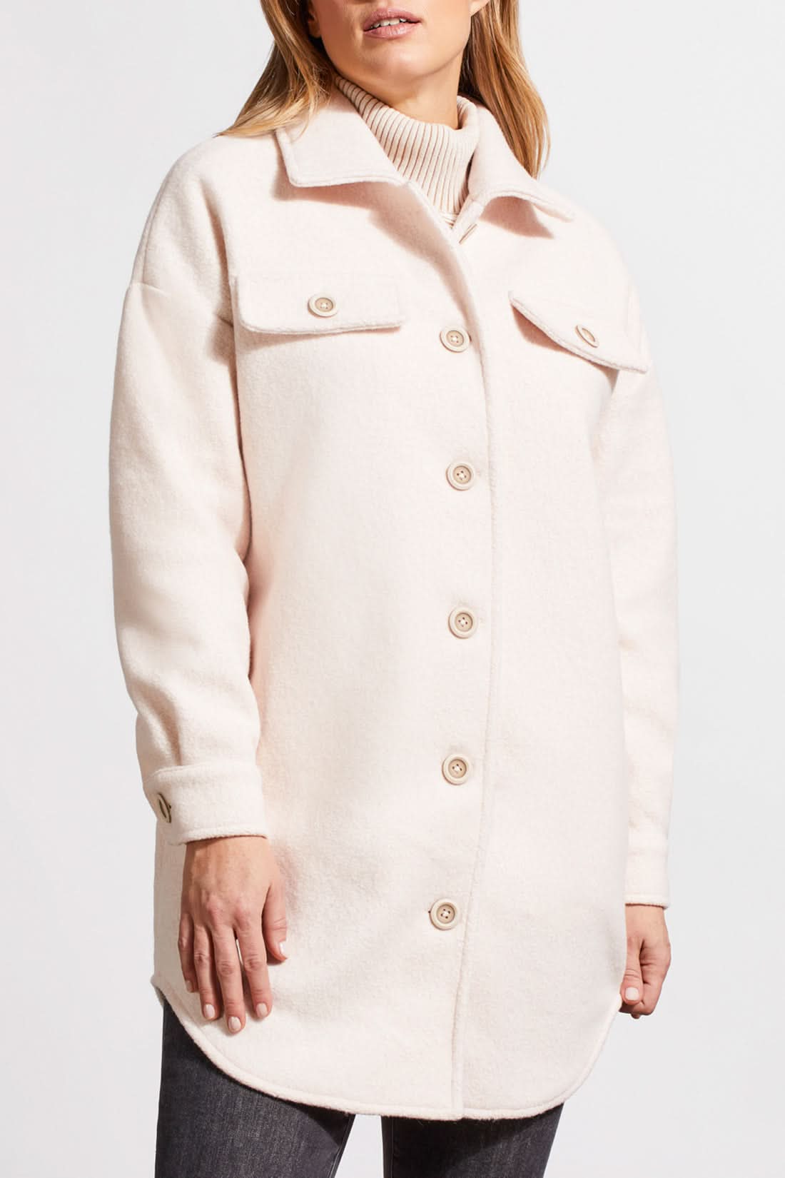 An individual with light hair is wearing a pale cream Stretch Boiled Wool Jacket by Tribal, featuring double-breasted button details. They are also dressed in a ribbed turtleneck sweater and are positioned against a plain background.