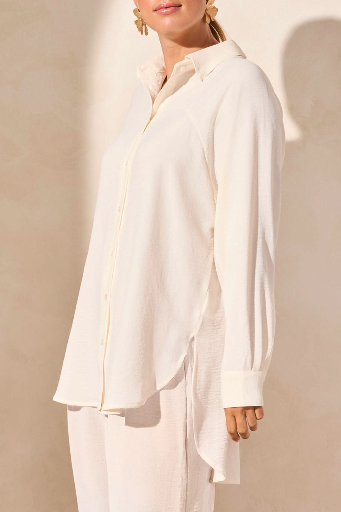 A person wearing the Tribal FLOWY RAGLAN SLEEVE SHIRT in brown, paired with loose-fitting pants, stands against a plain light-colored background.