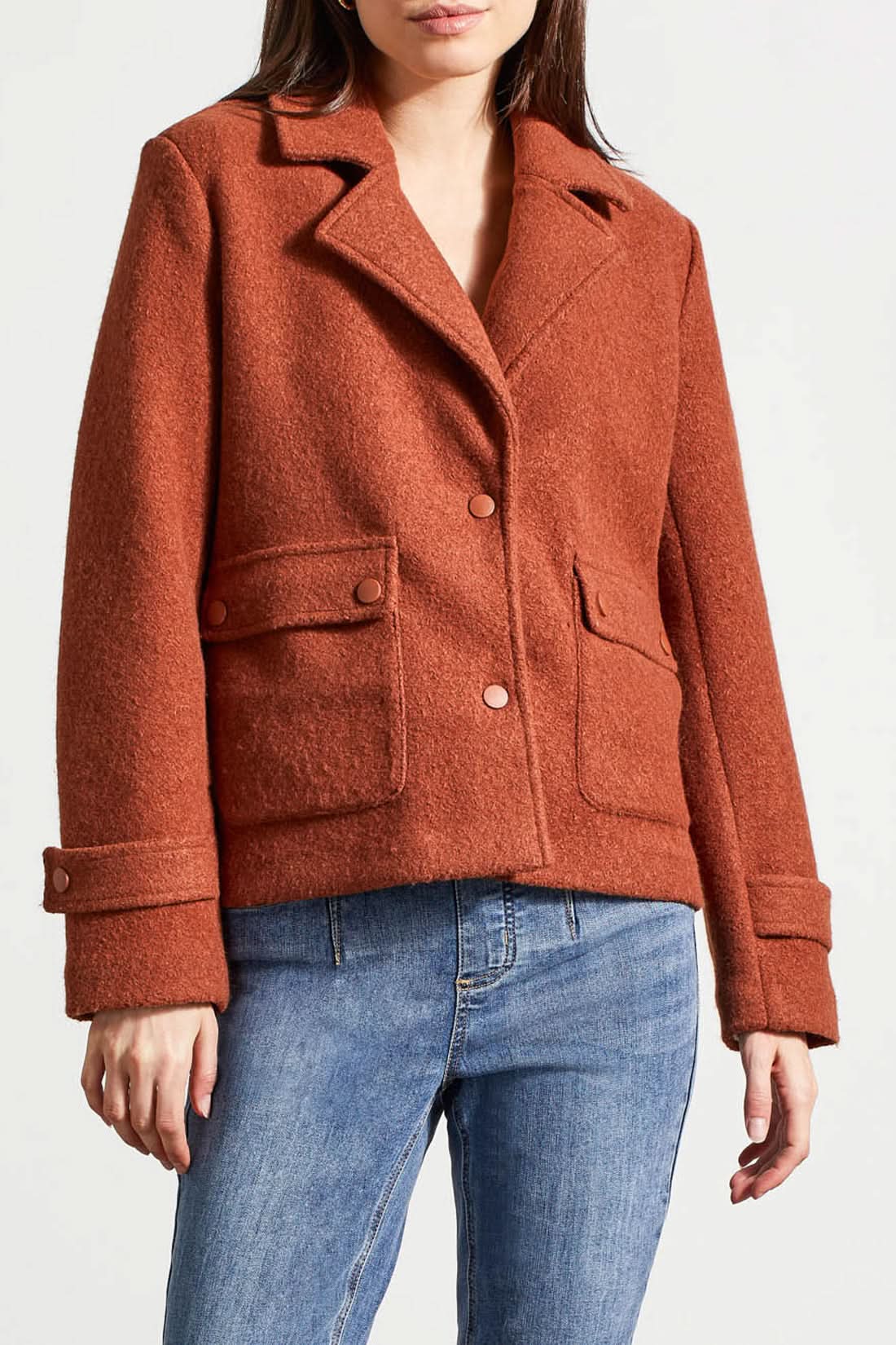 A person is wearing a stylish and warm rust-colored Snap Front Closure Peacoat by Tribal, featuring buttoned pockets and cuffs, paired with blue jeans.
