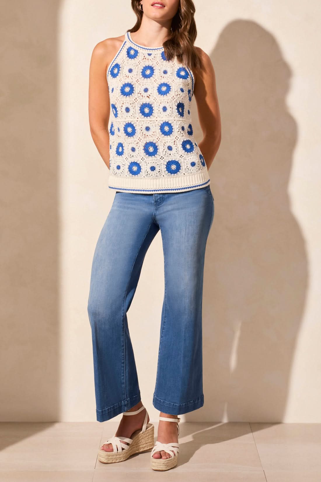 A woman in sunglasses, jeans, sandals, and the Tribal CROCHET COTTON RETRO SWEATER TANK walks beside a blue convertible on a sunny day.