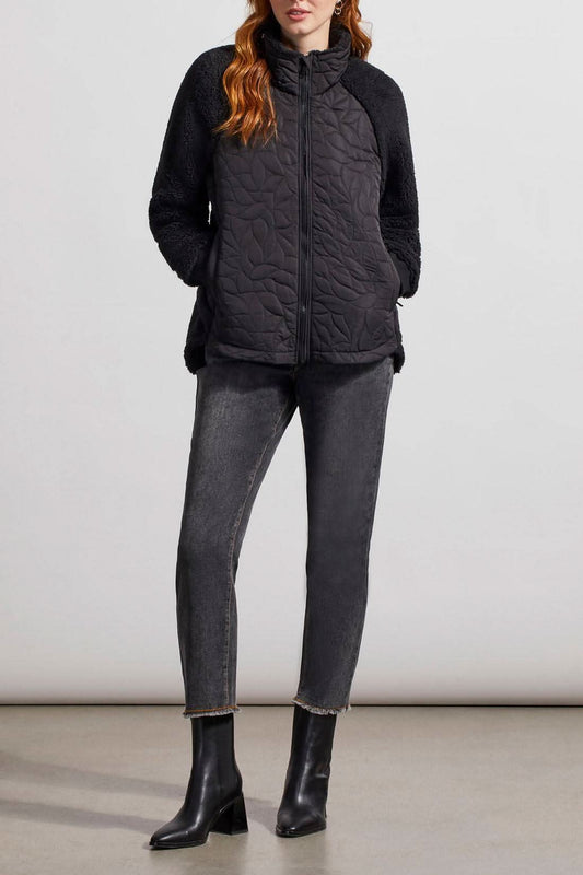 A woman wearing a Tribal Quilted Sherpa Jacket and jeans.