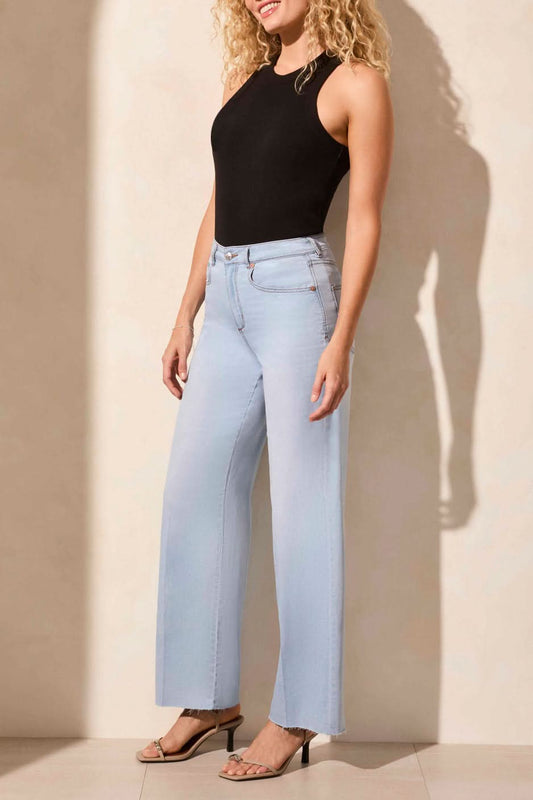 A person is shown from the waist down in natural light wearing Tribal’s BROOKE HUGGING WIDE TROUSER JEANS in light blue with a black sleeveless top.