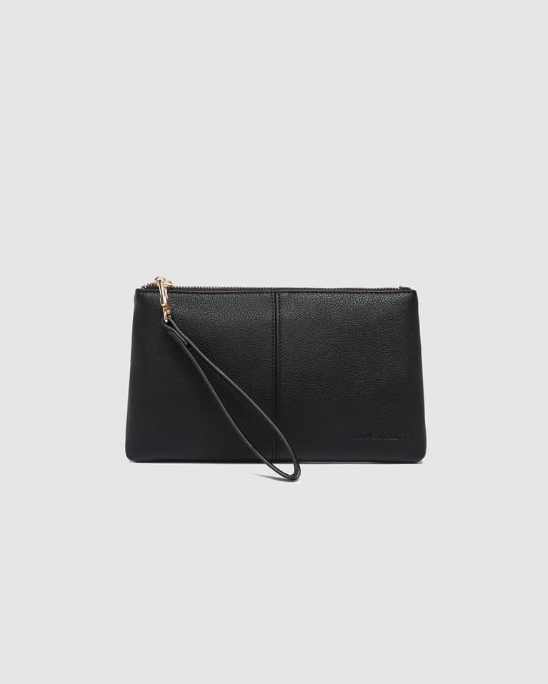 A person in white pants holds the Louenhide Mimi Gia Wristlet, a vegan leather accessory with a thick strap—an everyday essential for style and convenience, pictured standing indoors on steps.