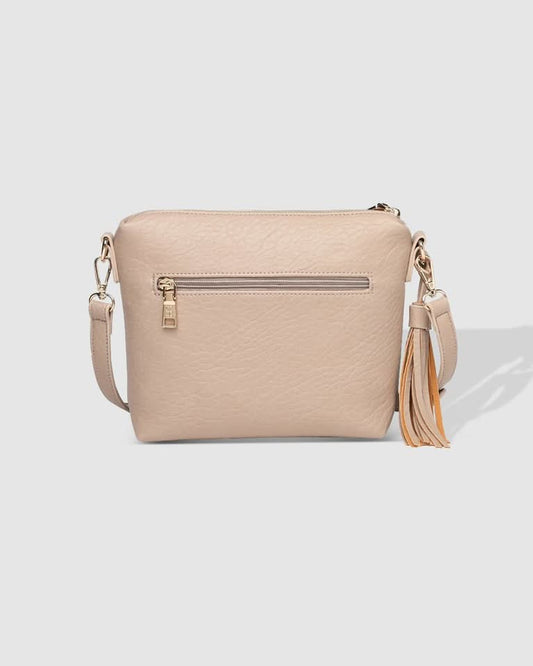 A person in a striped sleeveless top and pleated skirt carries the Louenhide Kasey Textured Crossbody Bag, featuring a wide strap and tassel.