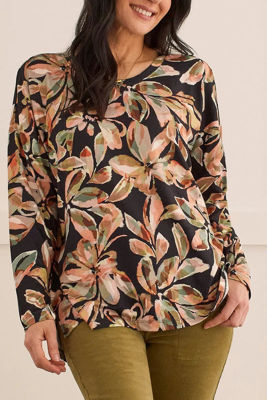 A woman wearing a Tribal Crew Neck Top With Side Slits, a comfortable fit black top with a floral pattern.