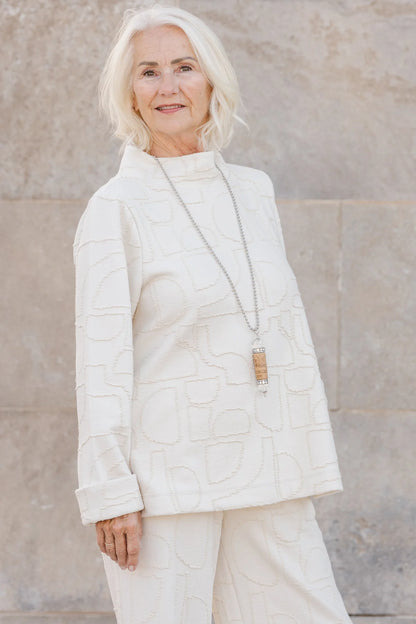 A woman wearing the Nile Pullover by Shannon Passero, a white jacquard top with artisanal details.