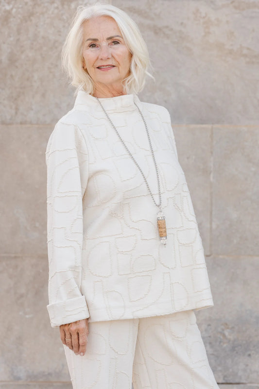 A woman wearing the Nile Pullover by Shannon Passero, a white jacquard top with artisanal details.