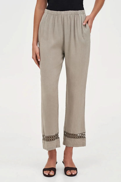 A person wearing M Made In Italy's Boho Trouser—beige linen straight-leg pants with an elastic waistband and cut-out hem details—paired with black open-toe sandals.