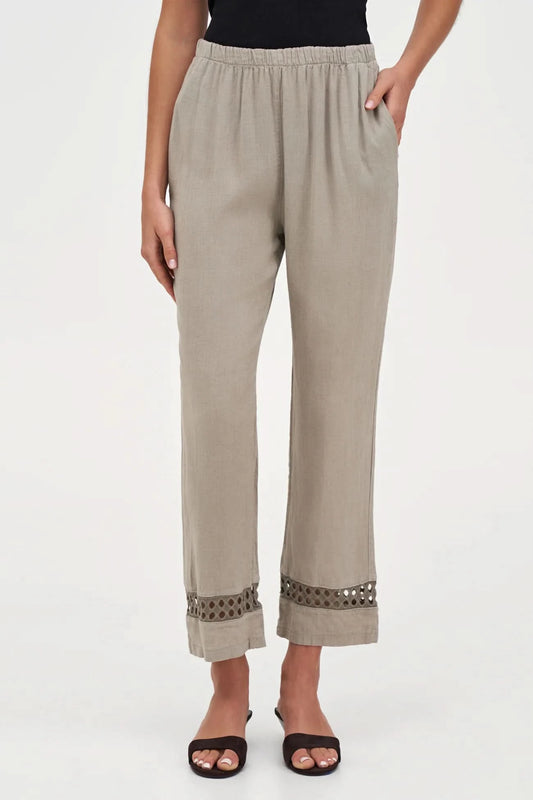 A person wearing M Made In Italy's Boho Trouser—beige linen straight-leg pants with an elastic waistband and cut-out hem details—paired with black open-toe sandals.