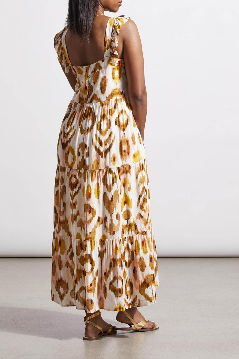 Woman in a versatile tie-dye patterned Tribal Flutter Strap Maxi Dress and brown sandals standing against a neutral background.