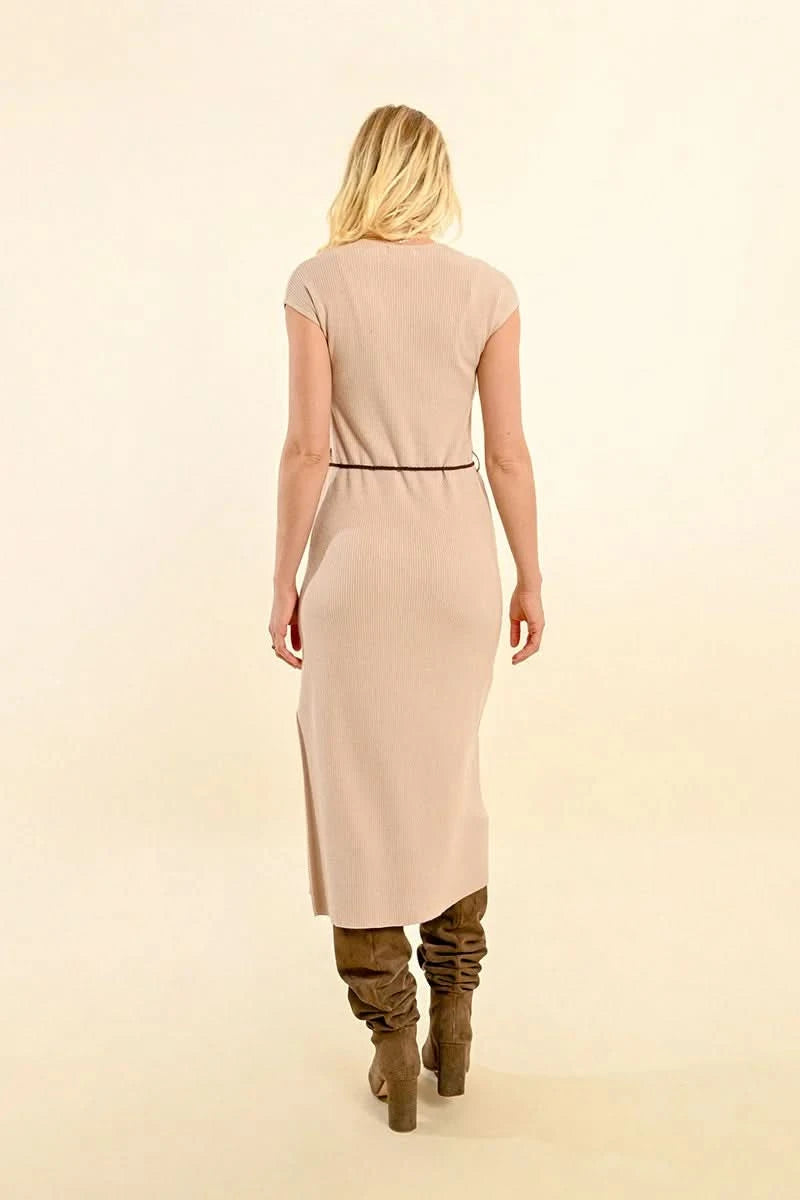 A person wearing the Molly Bracken Short Sleeve Ribbed Dress with Side Slit in beige, paired with a braided black belt and knee-high brown boots, stands against a light background.