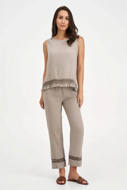 A person wearing M Made In Italy's Boho Trouser—beige linen straight-leg pants with an elastic waistband and cut-out hem details—paired with black open-toe sandals.