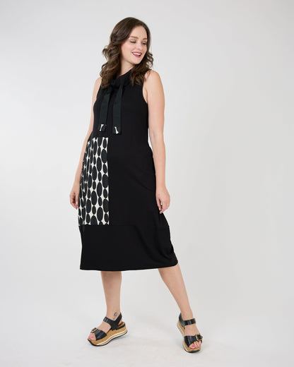 Woman smiling and posing in a unique Shannon Passero Black Patch Sullivan Dress with platform sandals.