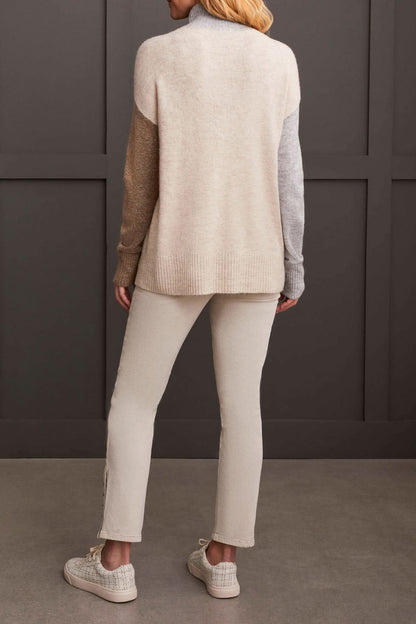 A person wearing the Mock Neck Colorblock Sweater by Tribal, featuring cozy gray, brown, and beige stripes, smiles while holding the collar near their face—truly a fall staple.